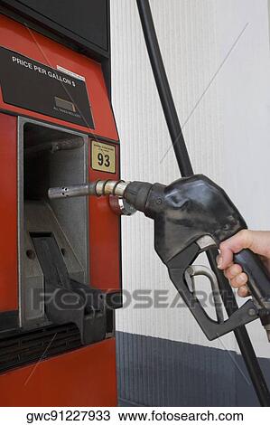 Stock Image - Person's hand holding a fuel pump at a gas station. Fotosearch