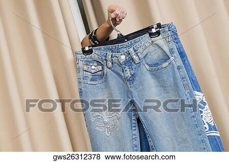 Stock Photo - Person's hand showing a jeans through curtains. Fotosearch