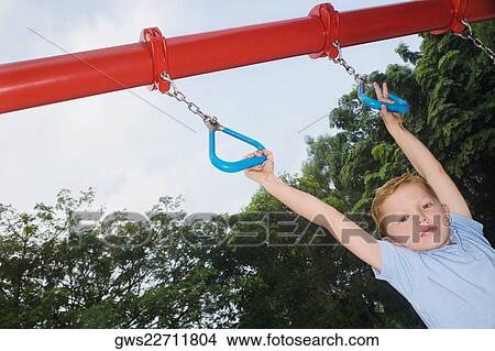 Picture - Portrait of a boy hanging on monkey bars. Fotosearch