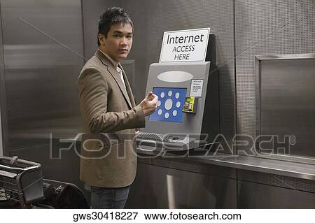 Stock Photo - Portrait of a businessman standing at a public internet point at an airport. Fotosearch