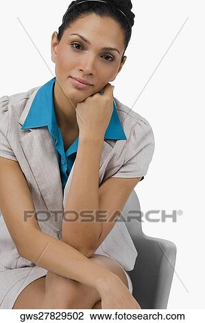 Stock Image - Portrait of a businesswoman sitting on a chair with her hand on her chin. Fotosearch