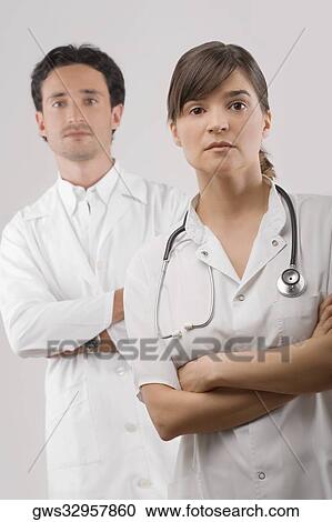 Portrait of a female and a male doctor standing with their arms crossed View Large Photo Image Stock Image - Portrait of a female and a male doctor standing with their arms crossed. Fotosearch