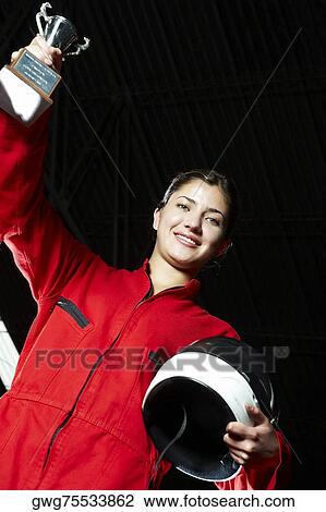 Portrait of a female go-cart racer holding a trophy with her hand raised and smiling View Large Photo Image Stock Image - Portrait of a female go-cart racer holding a trophy with her hand raised and smiling. Fotosearch