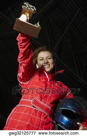 Portrait of a female go-cart racer holding a trophy and smiling View Large Photo Image Stock Photo - Portrait of a female go-cart racer holding a trophy and smiling. Fotosearch