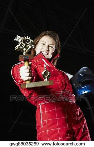 Portrait of a female go-cart racer showing her trophy and smiling View Large Photo Image Stock Photo - Portrait of a female go-cart racer showing her trophy and smiling. Fotosearch