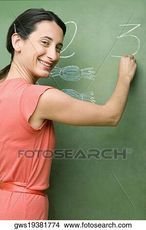 Portrait of a female teacher writing on a blackboard View Large Photo Image Picture - Portrait of a female teacher writing on a blackboard. Fotosearch