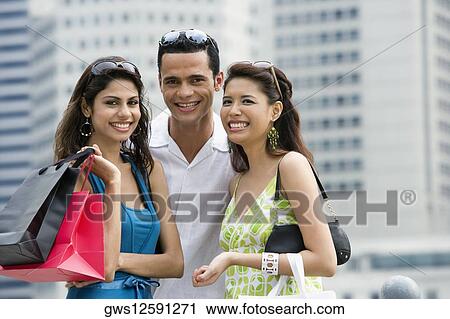 Stock Image - Portrait of a mid adult man and two young women smiling. Fotosearch