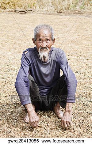 Portrait of a senior man crouching over rice grains, Zhigou, Shandong Province, China View Large Photo Image Stock Photography - Portrait of a senior man crouching over rice grains, Zhigou, Shandong Province, China. Fotosearch