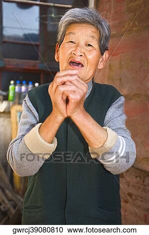 Portrait of a senior woman standing with hands clasped, HohHot, Inner Mongolia, China View Large Photo Image Stock Image - Portrait of a senior woman standing with hands clasped, HohHot, Inner Mongolia, China. Fotosearch