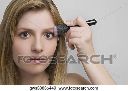 Portrait of a teenage girl applying blush on her face View Large Photo Image Stock Photo - Portrait of a teenage girl applying blush on her face. Fotosearch