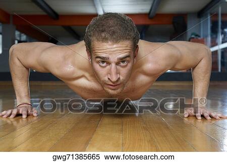 Stock Photography - Portrait of a young man doing push-ups. Fotosearch