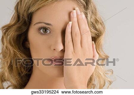 Portrait of a young woman covering her one eye View Large Photo Image Picture - Portrait of a young woman covering her one eye. Fotosearch