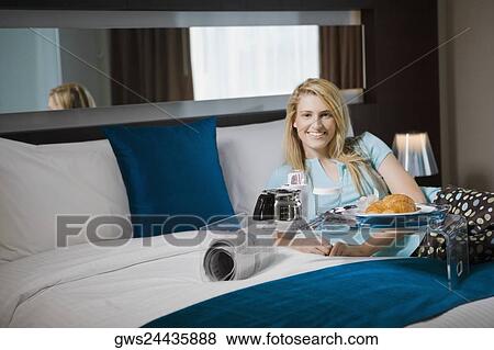 Portrait of a young woman having breakfast on the bed View Large Photo Image Stock Photo - Portrait of a young woman having breakfast on the bed. Fotosearch
