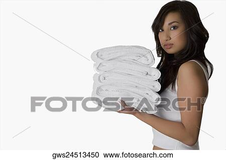 Stock Image - Portrait of a young woman holding folded towels. Fotosearch