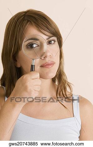 Stock Photography - Portrait of a young woman looking through a magnifying glass. Fotosearch