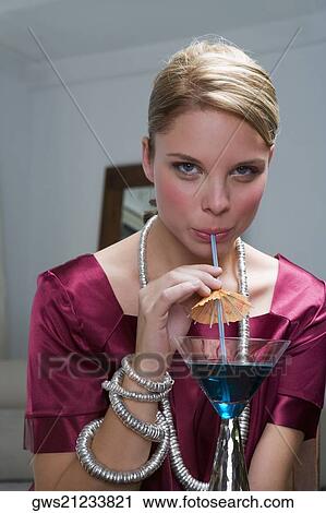 Portrait of a young woman sipping a cocktail View Large Photo Image Stock Image - Portrait of a young woman sipping a cocktail. Fotosearch