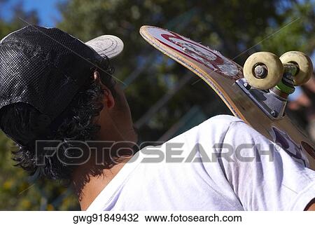 Stock Image - Rear view of a man with a skateboard. Fotosearch