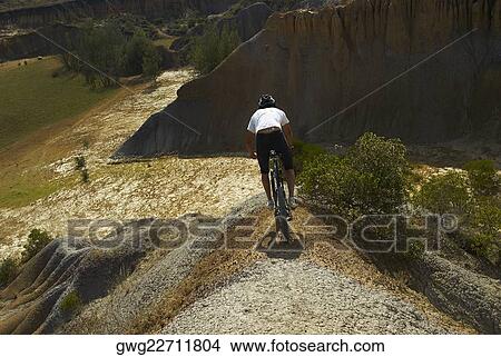 Rear view of a young man mountain biking View Large Photo Image Picture - Rear view of a young man mountain biking. Fotosearch