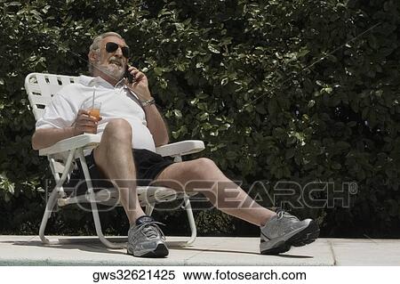 Senior man sitting on a chair and talking on a mobile phone View Large Photo Image Stock Photography - Senior man sitting on a chair and talking on a mobile phone. Fotosearch
