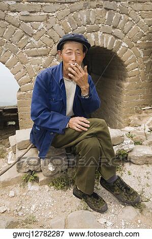 Stock Photo - Senior man smoking on a wall, Great Wall Of China, Beijing, China. Fotosearch