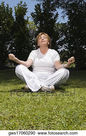 Stock Image - Senior woman sitting in lotus position. Fotosearch