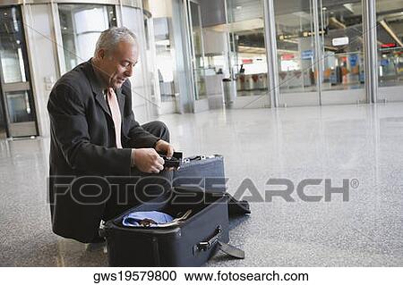 Side profile of a businessman packing his suitcase at an airport View Large Photo Image Stock Image - Side profile of a businessman packing his suitcase at an airport. Fotosearch