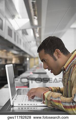 Side profile of a businessman using a laptop at an airport check-in counter View Large Photo Image Stock Photo - Side profile of a businessman using a laptop at an airport check-in counter. Fotosearch