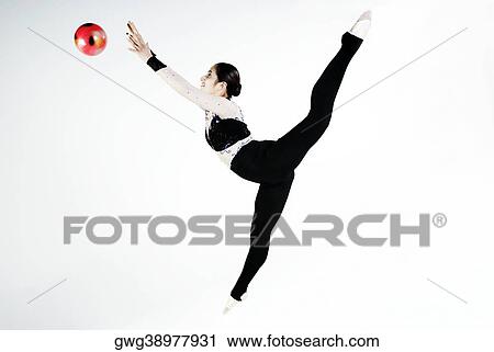 Stock Image - Side profile of a female gymnast practicing with a ball. Fotosearch