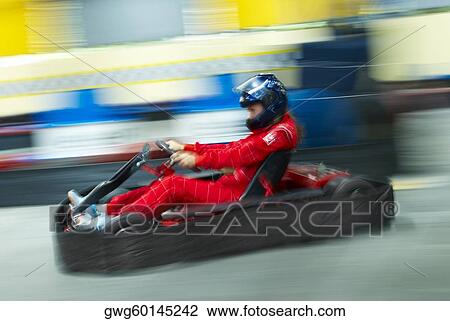 Stock Image - Side profile of a person go-carting on a motor racing track. Fotosearch