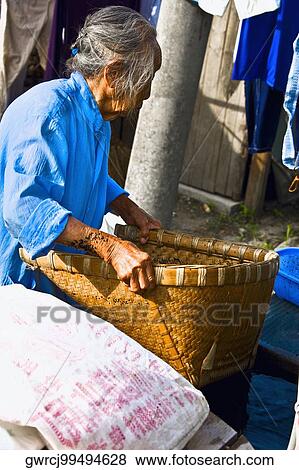 Stock Photo - Side profile of a senior woman holding a basket, Emerald Valley, Huangshan, Anhui Province, China. Fotosearch
