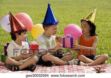 Picture - Three children sitting together on a picnic blanket. Fotosearch