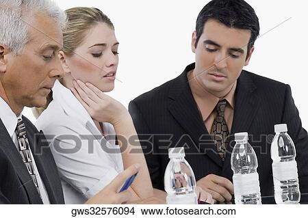 Two businessmen and a businesswoman at a meeting in a conference room View Large Photo Image Picture - Two businessmen and a businesswoman at a meeting in a conference room. Fotosearch