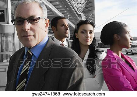 Stock Photo - Two businessmen standing at an airport with two businesswomen. Fotosearch