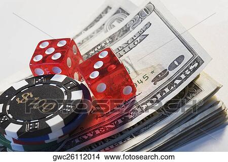 Two dices with a gambling chip on a stack of US dollar bills View Large Photo Image Picture - Two dices with a gambling chip on a stack of US dollar bills. Fotosearch