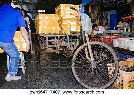 Stock Photo - Two people loading package into a cart, Shamian Island, Guangzhou, Guangdong Province, China. Fotosearch