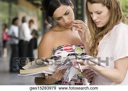 Two young women looking at a book View Large Photo Image Stock Photo - Two young women looking at a book. Fotosearch