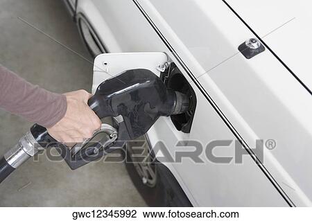 Stock Image - Woman refueling a car at a gas station. Fotosearch