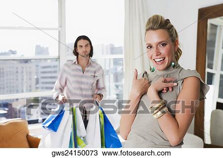 Young woman laughing with a young man holding shopping bags behind her View Large Photo Image Stock Image - Young woman laughing with a young man holding shopping bags behind her. Fotosearch