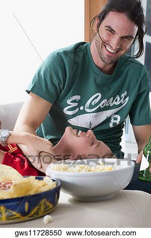 Stock Image - Young woman lying on the lap of a young man and smiling. Fotosearch