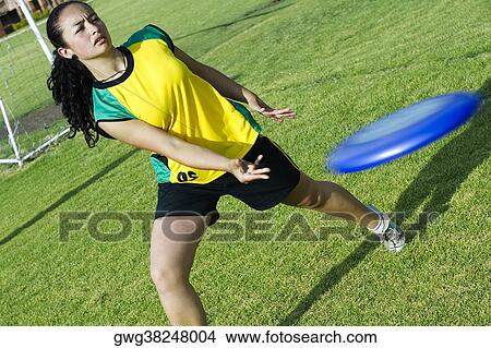 Young woman playing with a plastic disc in a park View Large Photo Image Picture - Young woman playing with a plastic disc in a park. Fotosearch