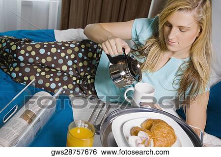 Stock Photograph - Young woman pouring tea into a tea cup. Fotosearch