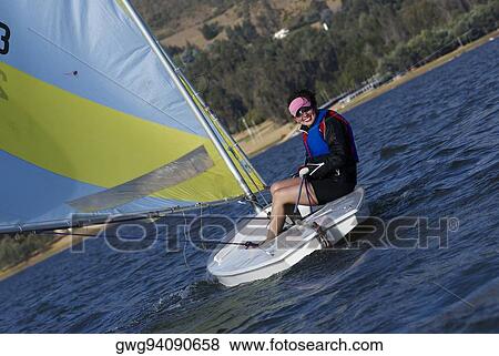 Stock Photo - Young woman sitting in a sailboat and smiling. Fotosearch