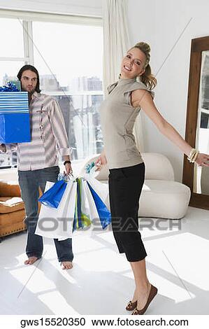Young woman smiling with a young man holding shopping bags beside her View Large Photo Image Stock Image - Young woman smiling with a young man holding shopping bags beside her. Fotosearch
