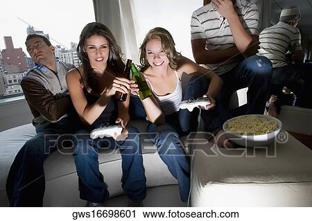Young women playing a video game and toasting with beer bottles View Large Photo Image Stock Image - Young women playing a video game and toasting with beer bottles. Fotosearch