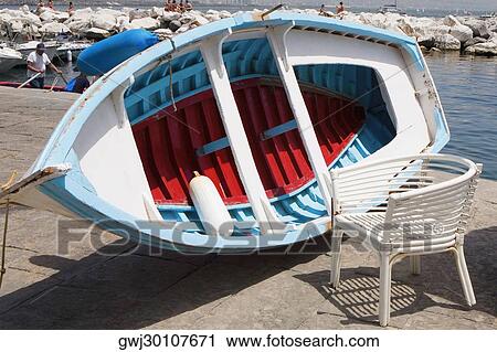 Stock Image - Boat with a chair at the coast, Bay of Naples, Naples, Naples Province, Campania, Italy. Fotosearch