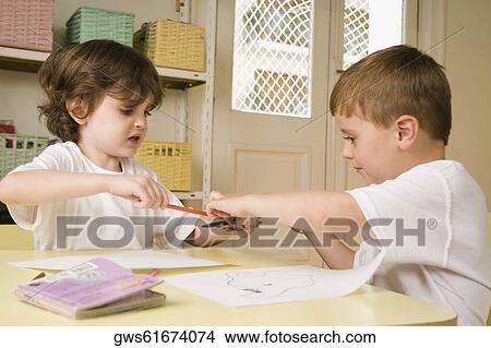 Picture - Boy snatching a pencil from a girl in a classroom. Fotosearch