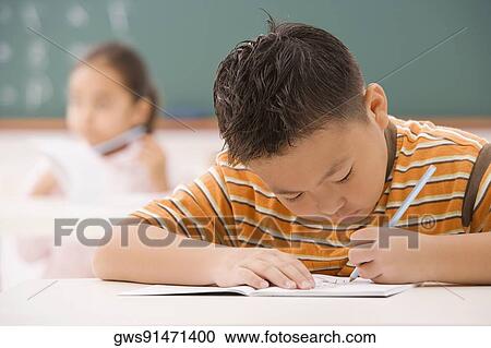 Boy writing on a notepad in a classroom View Large Photo Image Stock Image - Boy writing on a notepad in a classroom. Fotosearch