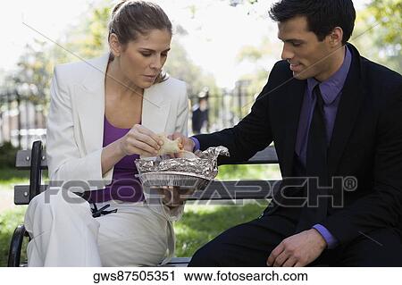 Businessman and a businesswoman having food on a park bench View Large Photo Image Stock Image - Businessman and a businesswoman having food on a park bench. Fotosearch