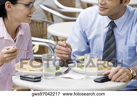 Stock Photo - Businessman and a businesswoman having lunch at a sidewalk cafe. Fotosearch