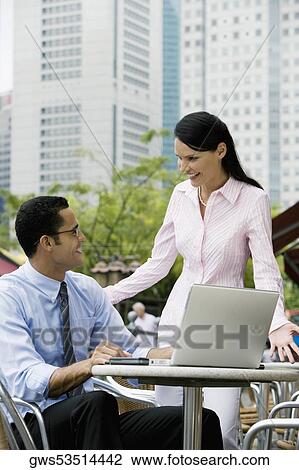 Stock Image - Businessman and a businesswoman looking at each other and smiling. Fotosearch